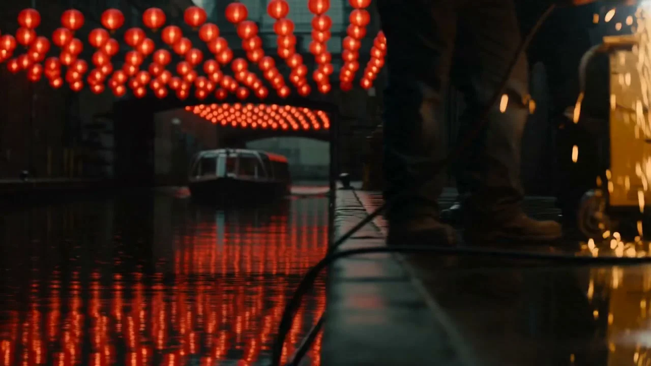 Welding sparks and workers at water level beneath red lanterns. Supplied generated shot study.